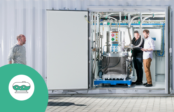 Researchers working on a hydrogen liquefier in a technical facility.