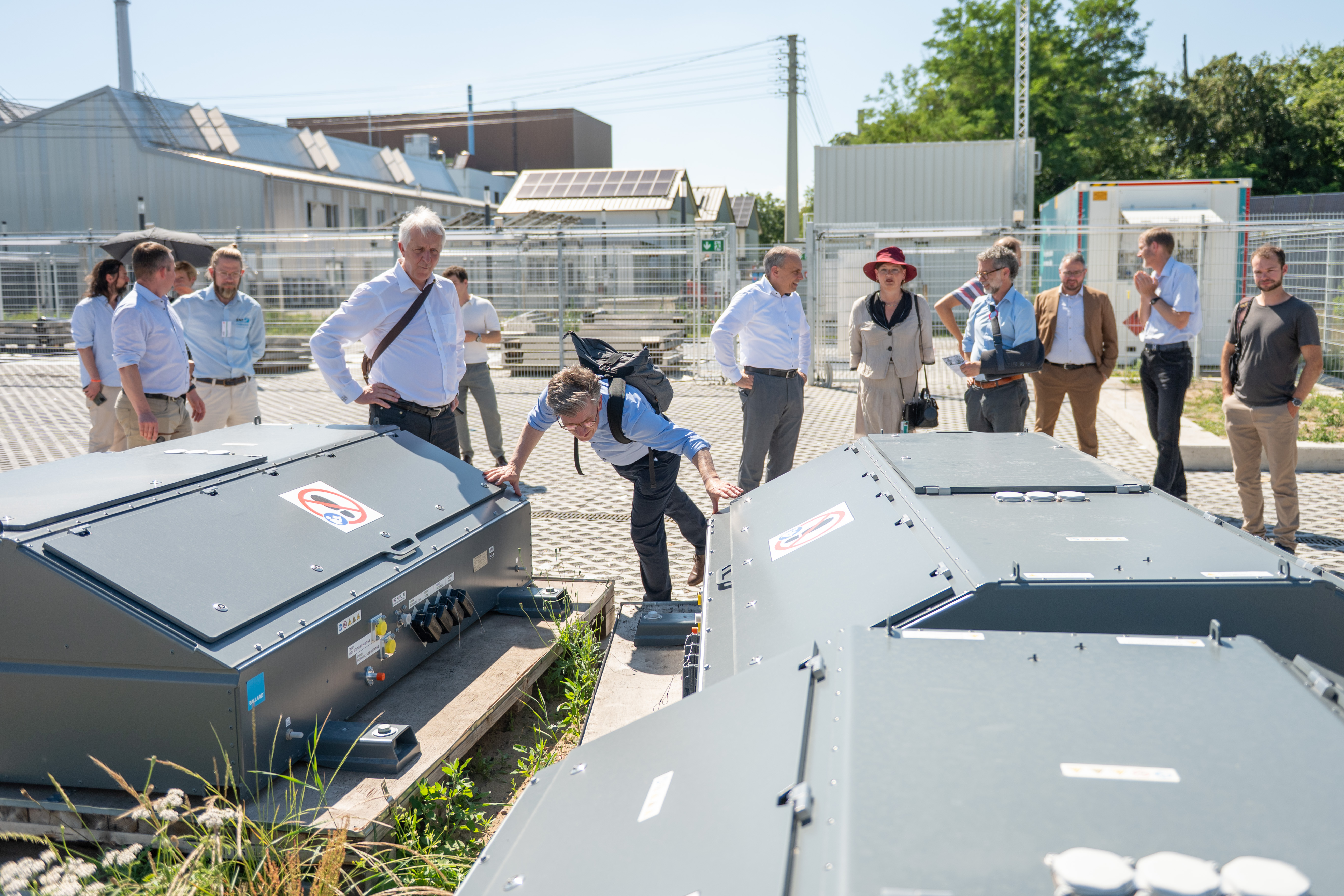 Gruppe von Fachleuten begutachtet große graue Industriecontainer im Außenbereich.